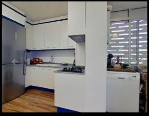 una cucina con armadi bianchi e frigorifero in acciaio inossidabile di Apartamento con piscina y cerca de la playa a Benicàssim