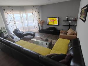 una sala de estar con un sofá de cuero negro y sillas en 3 bedrooms Apartman DMT en Kaštela
