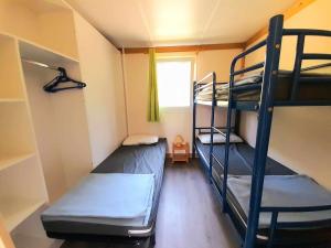 Cette chambre comprend 2 lits superposés et une fenêtre. dans l'établissement Les Auzerals camping du lac, à Rabastens