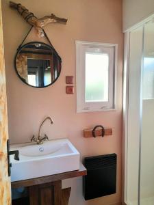 La salle de bains est pourvue d'un lavabo blanc et d'un miroir. dans l'établissement Les Auzerals camping du lac, à Rabastens