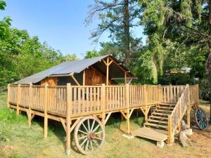 une yourte en bois avec un wagon en bois dans l'herbe dans l'établissement Les Auzerals camping du lac, à Rabastens