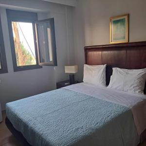 a bedroom with a bed with a blue comforter and a window at Apartment beside the sea in Hanioti