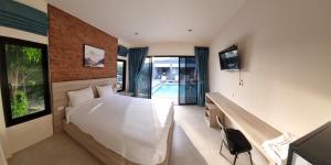 a bedroom with a bed and a desk and a tv at Bests Village & Villa - Chalong Bay Phuket in Chalong