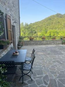 eine Terrasse mit einem Tisch und Stühlen auf einer Steinterrasse in der Unterkunft Al Buffardel in Bagnone