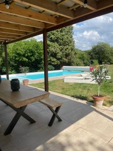 a patio with a wooden table and a pool at Le Castel Mosan in Namur