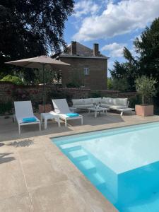 - une piscine avec 2 chaises longues et un parasol dans l'établissement Le loft du Castel Mosan, à Namur