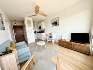een woonkamer met een blauwe bank en een flatscreen-tv bij T2 refait à neuf – À 2 pas du bourg et des plages in Larmor-Plage