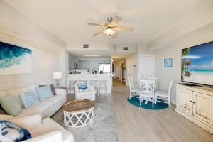 a living room with a white couch and a tv at Calypso Tower 3 - Endless Sunsets and Gulf Coast View! in Panama City Beach