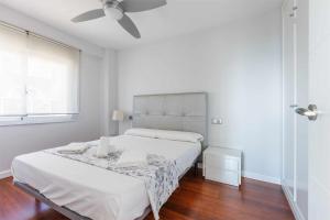 een witte slaapkamer met een bed en een plafondventilator bij A&N San Gerardo 123 in Torre del Mar