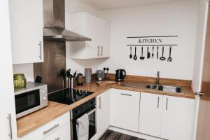 a kitchen with white cabinets and a microwave at Modern Centre of the city 1 bedroom apartment in Sheffield