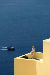 a man sitting on the edge of a building looking at the ocean at Ilivatos in Oia