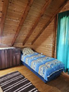 a bed in a room with a wooden ceiling at Planinska tišina Guest House in Pluzine