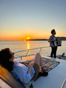 a woman sitting on a boat watching the sunset at Lovely Lobster in the Island in Adalar