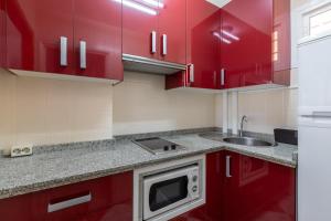 a kitchen with red cabinets and a microwave at Apartamento vistas a piscina in Benalmádena