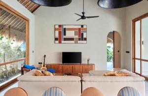 a living room with two couches and a tv at Boni Beach Lombok Boutique Hotel in Selong Belanak