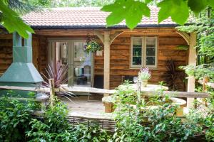 a log cabin with a porch and a porch swing at HAYNE BARN ESTATE ECOLODGES in Hythe