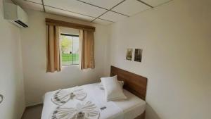 - une chambre avec un lit doté de draps blancs et une fenêtre dans l'établissement Pousada São José, à Joinville