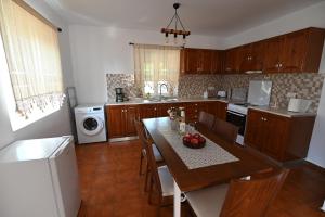 a kitchen with a table and chairs and a kitchen with a refrigerator at Traditional Kos villa with swimming pool, lawn yard and bbq in Kos