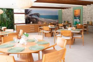 a restaurant with wooden tables and chairs and a beach at Charmoso Estúdio em Muro Alto com Vista para piscina in Porto De Galinhas