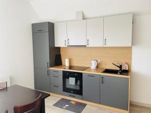 a kitchen with white cabinets and a black oven at Apartament Brzóza Królewska in Brzóza Królewska