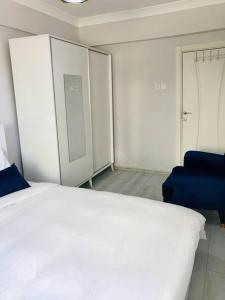 ein Schlafzimmer mit einem weißen Bett und einem blauen Stuhl in der Unterkunft Sea View Modern Appartement with a Privet Garden in Çiftlikköy