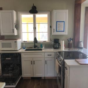 a kitchen with white cabinets and a sink and a microwave at Seabreeze Three Bedroom Home in Rochester