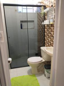 La salle de bains est pourvue de toilettes et d'une douche avec un tapis vert. dans l'établissement Casa refúgio, à Cavalcante