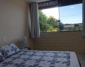 ein Schlafzimmer mit einem Bett und einem großen Fenster in der Unterkunft Casa refúgio in Cavalcante