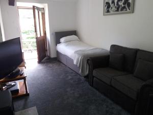 una camera con letto, divano e TV di NEWFIELD INN a Broughton-in-Furness