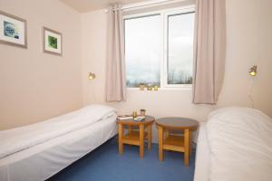 a room with two beds and a table and a window at Sjøholt Sommerhotell in Ørskog