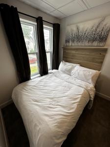 1 dormitorio con 1 cama blanca y ventana en Le Chambreur, en Rouyn