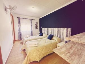 a bedroom with two beds and a purple wall at Fonda Aparicio in Fuentespalda