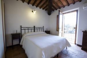 um quarto com uma cama branca e uma grande janela em Agriturismo Pontignanello em Siena