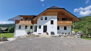 ein großes weißes Haus mit Holzdach in der Unterkunft Moamoosgut in Göriach