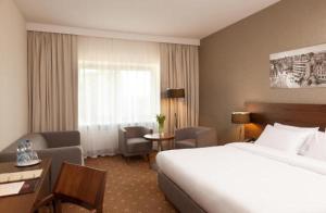 um quarto de hotel com uma cama, uma secretária e uma cadeira em Warmiński Hotel & Conference em Olsztyn