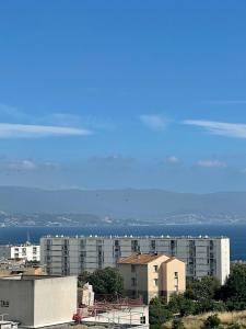 een stad met gebouwen en de oceaan op de achtergrond bij Appartement T3, dernier étage, vue dégagée in Ajaccio