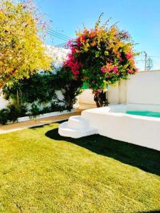 um jardim com um sofá branco na relva em Villa Buganvillas, relax con piscina privada a pocos minutos de la Barrosa y Santi Petri em Chiclana de la Frontera