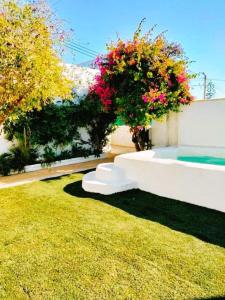 a garden with a white couch in the grass at Villa Buganvillas, relax con piscina privada a pocos minutos de la Barrosa y Santi Petri in Chiclana de la Frontera