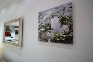 un miroir et une photo sur un mur orné de fleurs dans l'établissement Palais Miramar - Suite White Jardin - 20m Plage, à Cannes