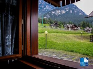a window with a view of a mountain at Dolomites Stunning View & Garden in San Vito di Cadore