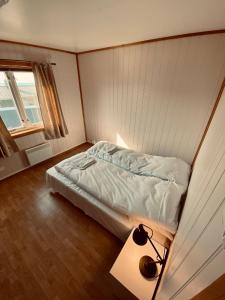 a bedroom with a bed and a table with a lamp at Ramberg Gjestegård in Ramberg