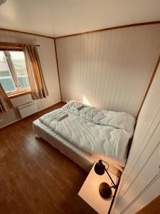ein Schlafzimmer mit einem Bett und einem Tisch mit einer Lampe in der Unterkunft Ramberg Gjestegård in Ramberg