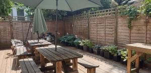 - une table en bois avec un parasol sur la terrasse dans l'établissement Barmy Badger Backpackers, à Londres