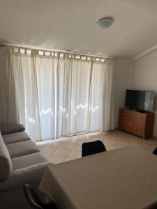 uma sala de estar com cortinas brancas e um sofá e uma televisão em Apartmani Iva em Biograd na Moru