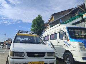 Ein weißer Truck und ein weißer Van stehen neben einem Gebäude. in der Unterkunft Hotel city way in Srinagar