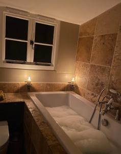 y baño con bañera y ventana. en Hound and Human Holiday Cottage - Redgrave, Suffolk en Diss