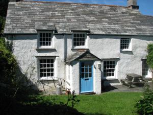 a white house with a blue door and a picnic table at The Old Farmhouse in Crackington Haven