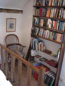 a book shelf filled with books next to a chair at The Old Farmhouse in Crackington Haven