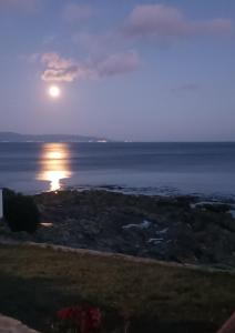 una luna piena che sale sull'oceano al tramonto di Casiña Palmira a Finisterre