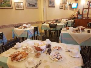 una sala da pranzo con tavoli e piatti di Hotel Villa Ersilia Rimini B&B a Rimini
